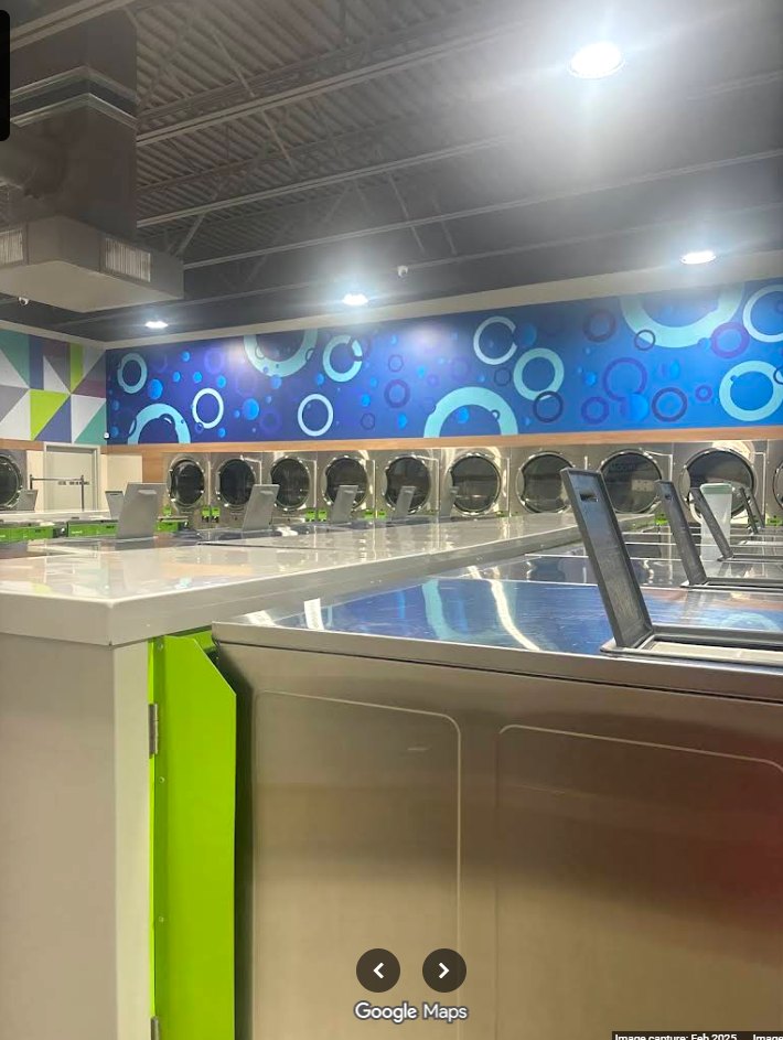 Row of front-load washers beneath the blue bubble mural at Fresh Wash Washateria